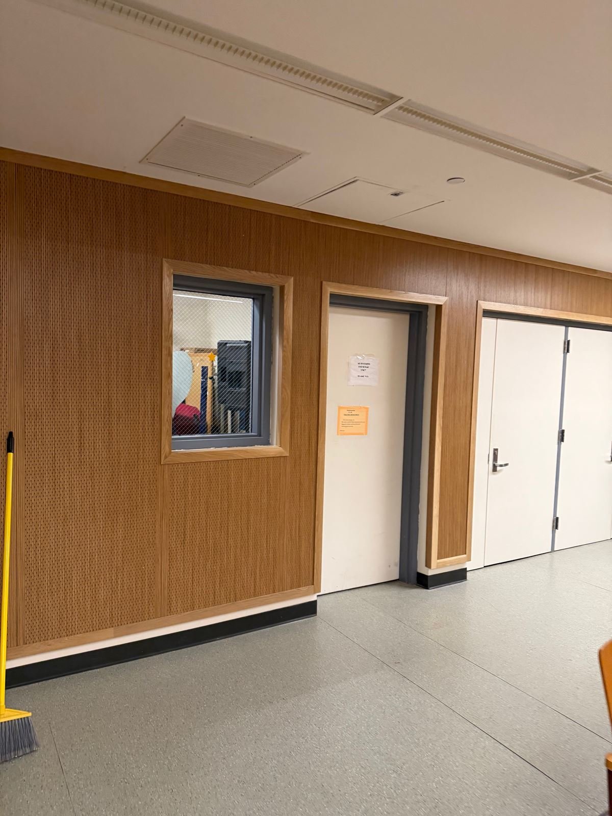 School corridor renovated with warm wood wall paneling, new door frames and resilient flooring