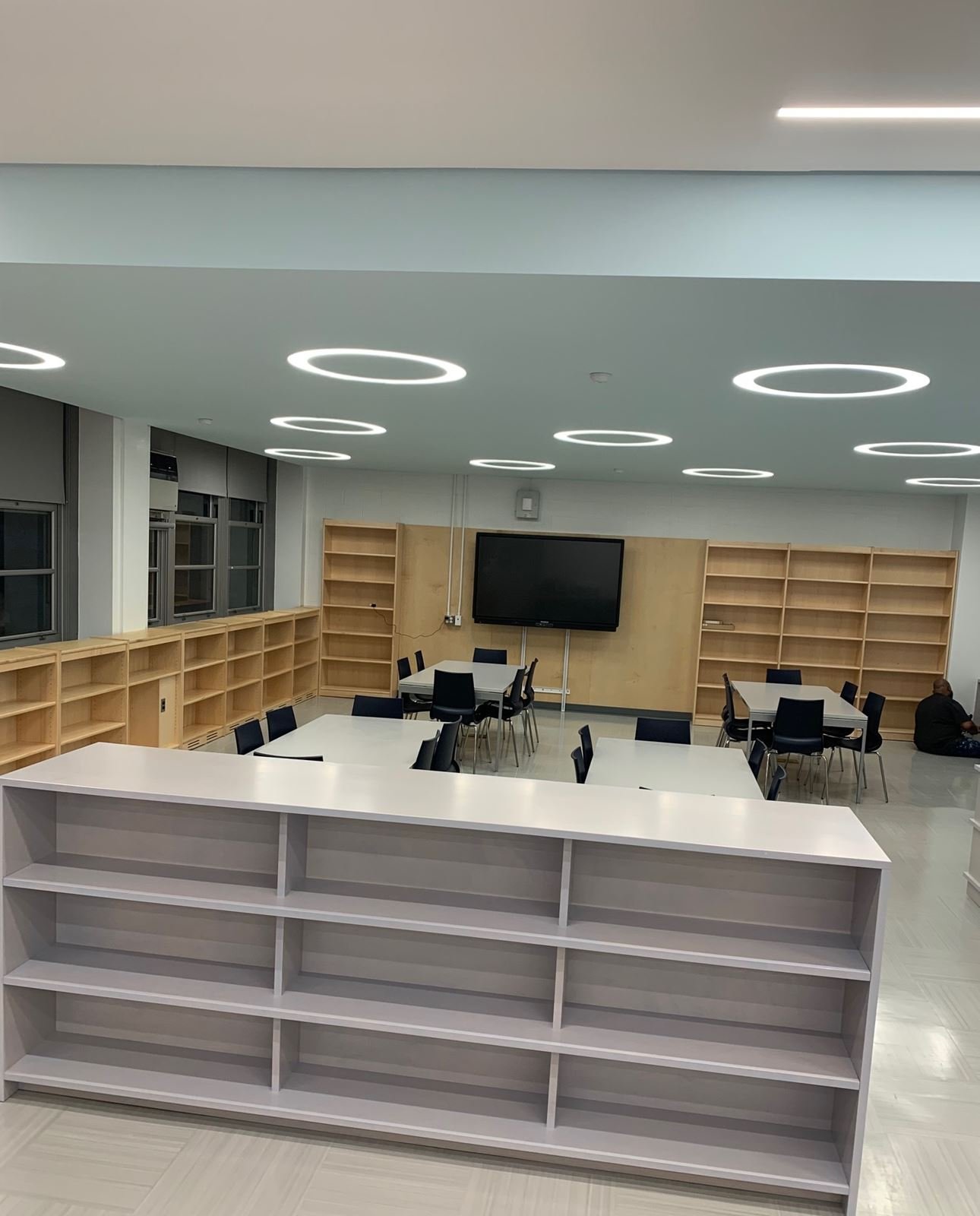 Refurbished library at I.S. 59 in Queens with ring lights, maple shelving and study tables